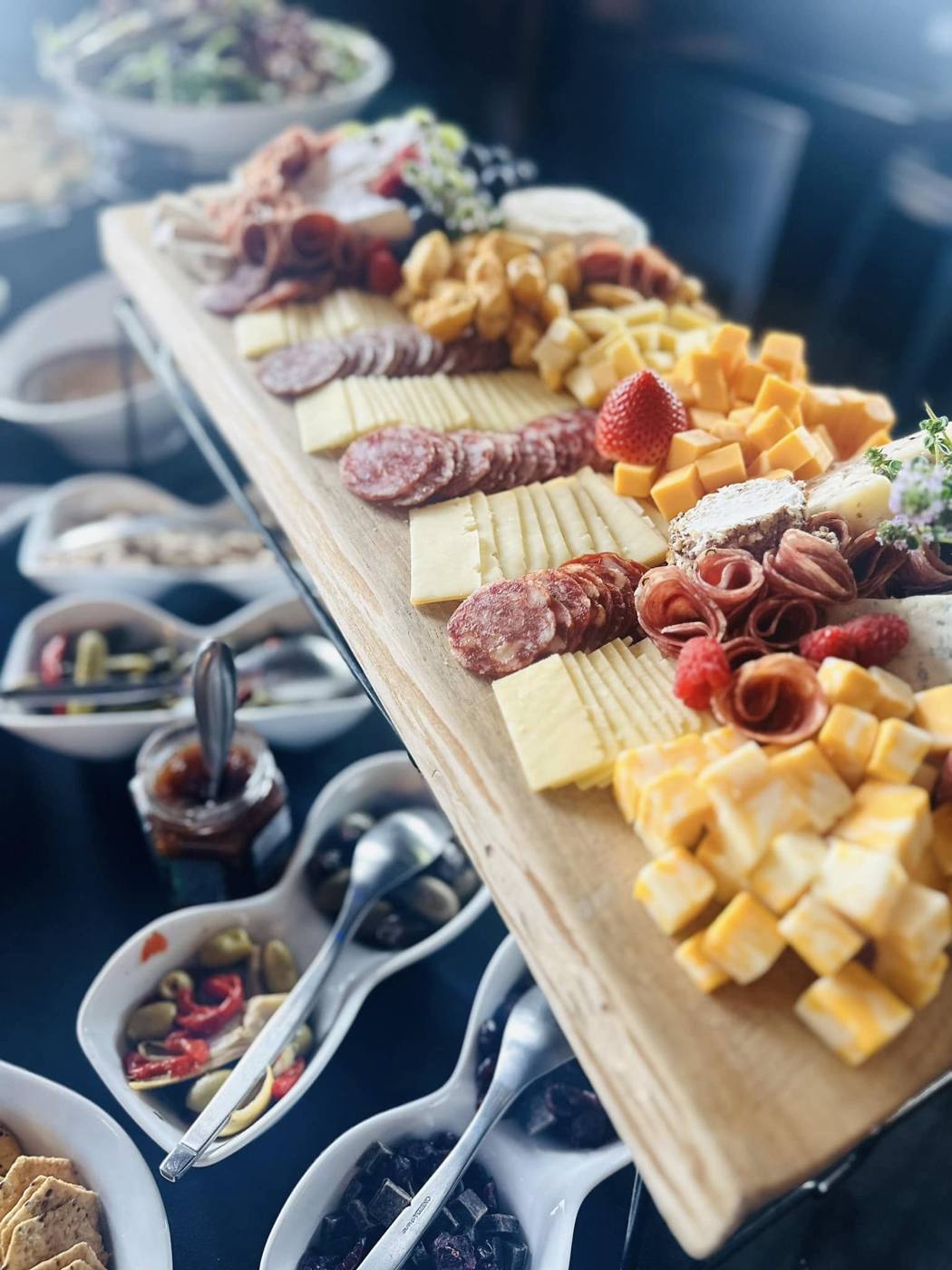 Long charcuterie board with salami roses, cheeses and berries